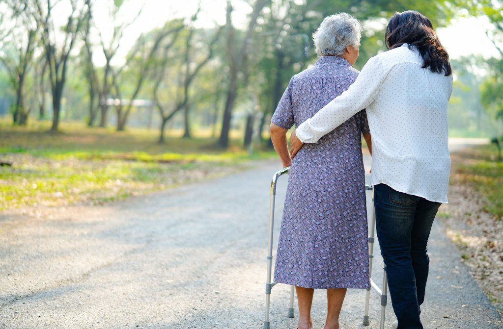 Eine ältere Frau wird bei einem Spaziergang mit dem Rollator begleitet.